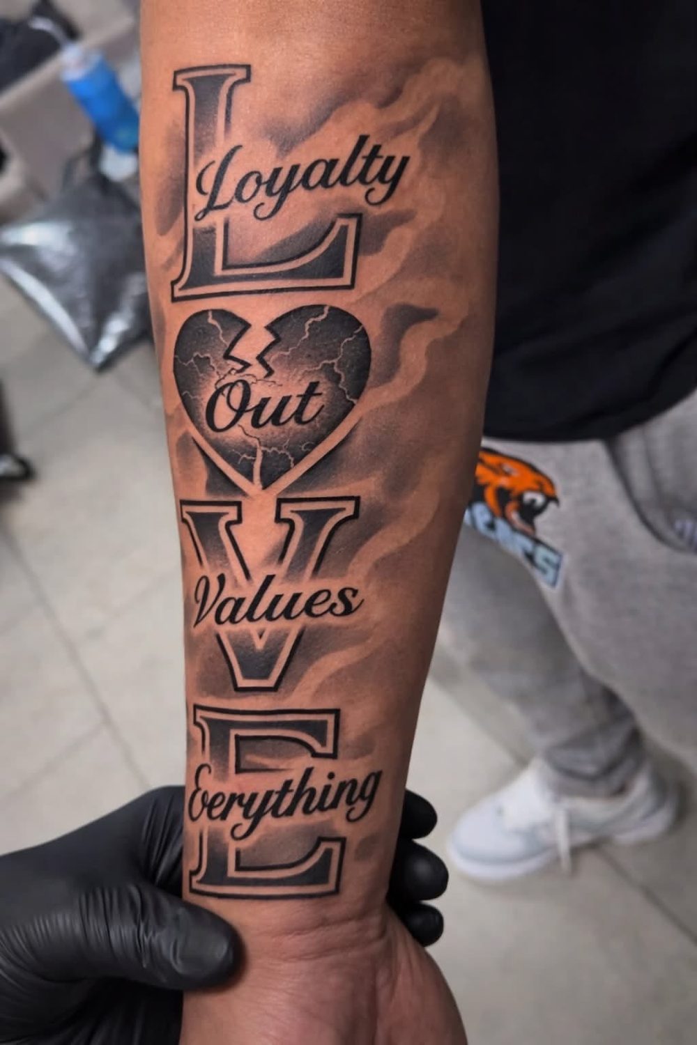LOVE lettering tattoo with broken heart, forearm